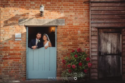 Bride and groom smiling in rustic doorway.