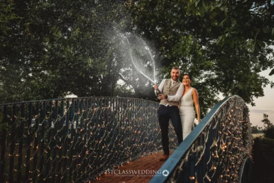 Couple celebrating with champagne on a decorated bridge