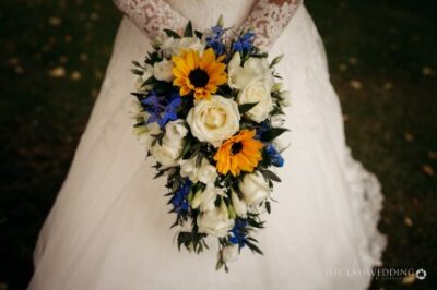 Bride holding vibrant sunflower and rose bouquet.