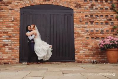 Bride embracing friend outside brick venue with black door