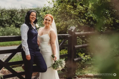 Two brides smiling outdoors on wedding day.