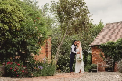 Couple embracing in garden on wedding day.