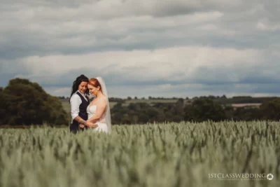 Bride and partner holding hands in field.