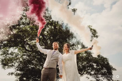 Couple with smoke flares at wedding celebration.