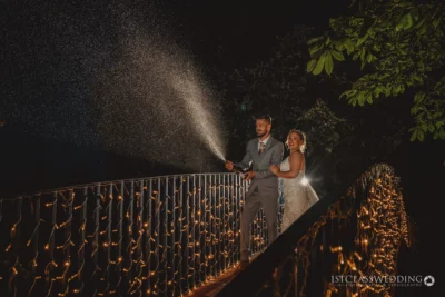Bride and groom with champagne spray at night wedding
