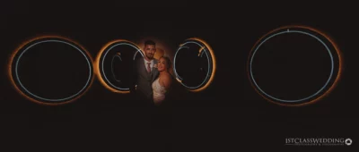 Bride and groom with illuminated rings backdrop at night.