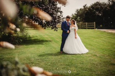 Bride and groom embracing in sunny garden setting