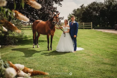 Bride, groom, and horse in rural wedding setting.