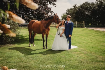 Bride, groom, and horse at countryside wedding.