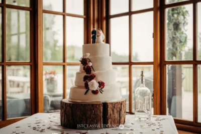 Elegant wedding cake with floral decor by window.