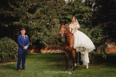 Bride on horse with groom in garden wedding setting.