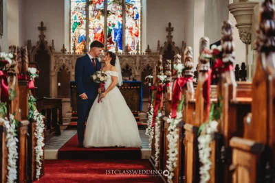 Wedding couple inside church, stained glass background.