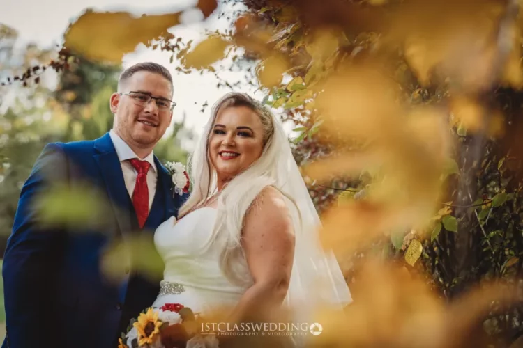 Bride and groom smiling outdoors, autumn wedding theme.