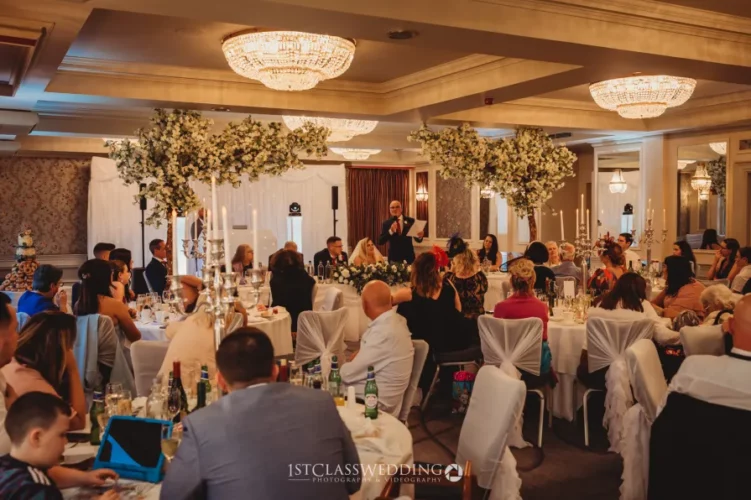 Elegant wedding reception speech with guests and decor.