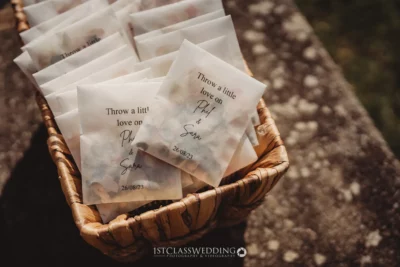 Wedding confetti packets in basket with couple's names.