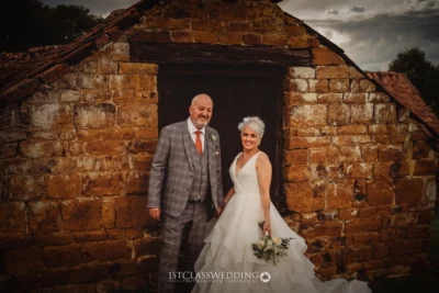 Couple posing on wedding day by rustic building.