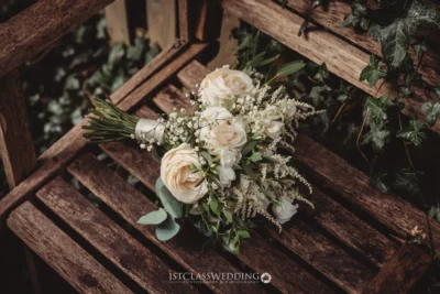 Elegant bridal bouquet on rustic wooden bench.