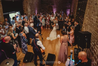 Joyful wedding reception dance in rustic venue.