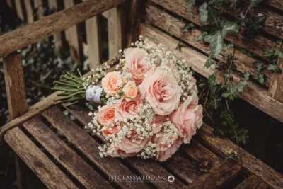 Peach roses bouquet on rustic wooden bench.