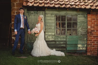 Bride and groom smiling outside rustic building.