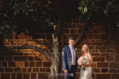 Couple posing for wedding photo outside with tree