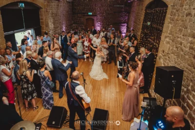 Wedding dance in a rustic venue with guests.