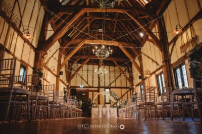 Rustic barn wedding venue interior setup with lighting.
