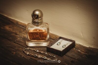 Perfume bottle, jewellery on wooden surface.