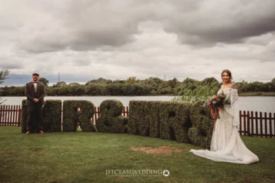 Bride and groom beside "Mr & Mrs" topiary at wedding.