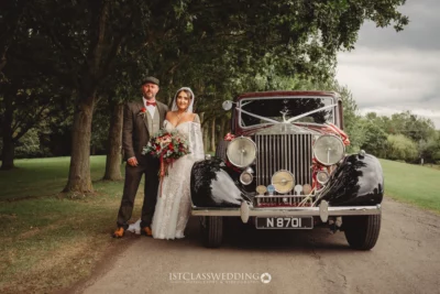 Bride and groom posing with vintage Rolls-Royce wedding car.