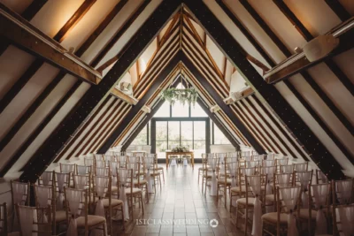 Elegant barn wedding venue with wooden beams and chairs.