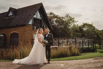 Bridal couple posing beside country house.