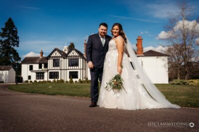 Bride and groom posing outside manor house.