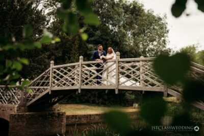 Couple on a bridge surrounded by greenery at wedding.