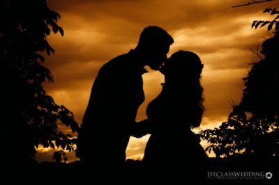 Couple's silhouette against sunset during romantic moment.