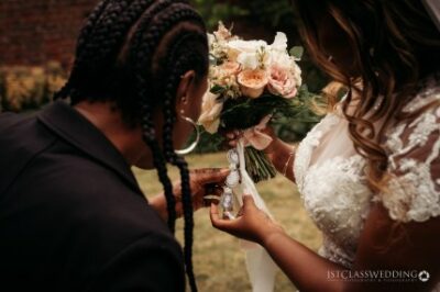 Bride receiving bouquet at wedding ceremony.