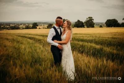 Couple embracing in field on wedding day.