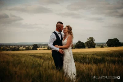 Couple embracing in a field on their wedding day.