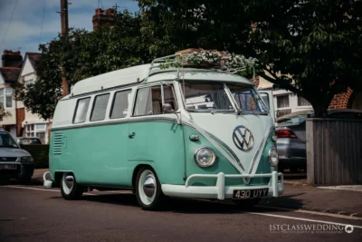 Vintage teal Volkswagen camper van on suburban street.
