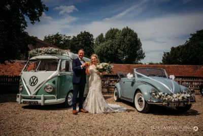 Wedding couple with classic VW camper and Beetle.