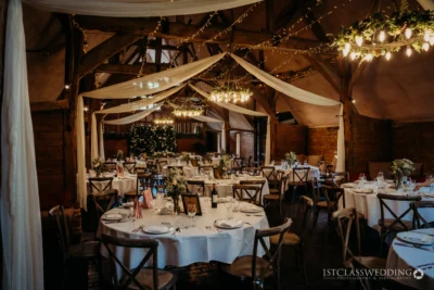 Rustic barn wedding reception setup with fairy lights.