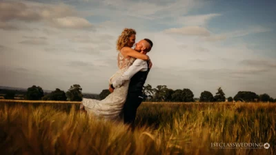 Couple embracing in wheat field at sunset.