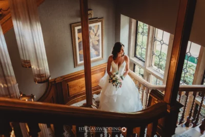 Bride in gown holding bouquet on staircase