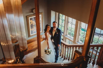 Elegant couple posing on historical staircase, wedding day.