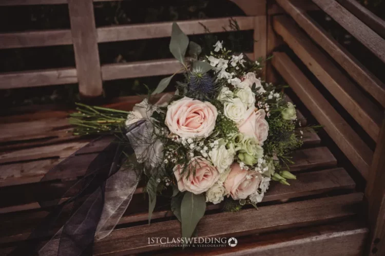 Elegant wedding bouquet on wooden bench.