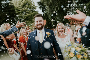 Joyful wedding couple with confetti celebration.