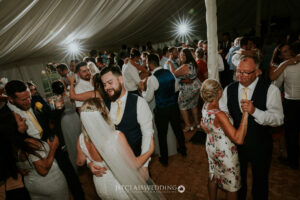 Guests dancing at wedding reception under marquee.
