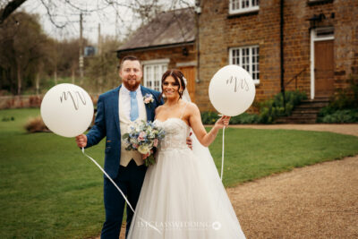 Bride and groom holding balloons at UK wedding venue.