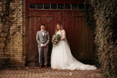 Bride and groom posing by rustic red door.