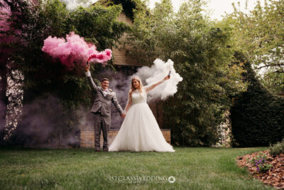 Bride and groom with colorful smoke flares in garden